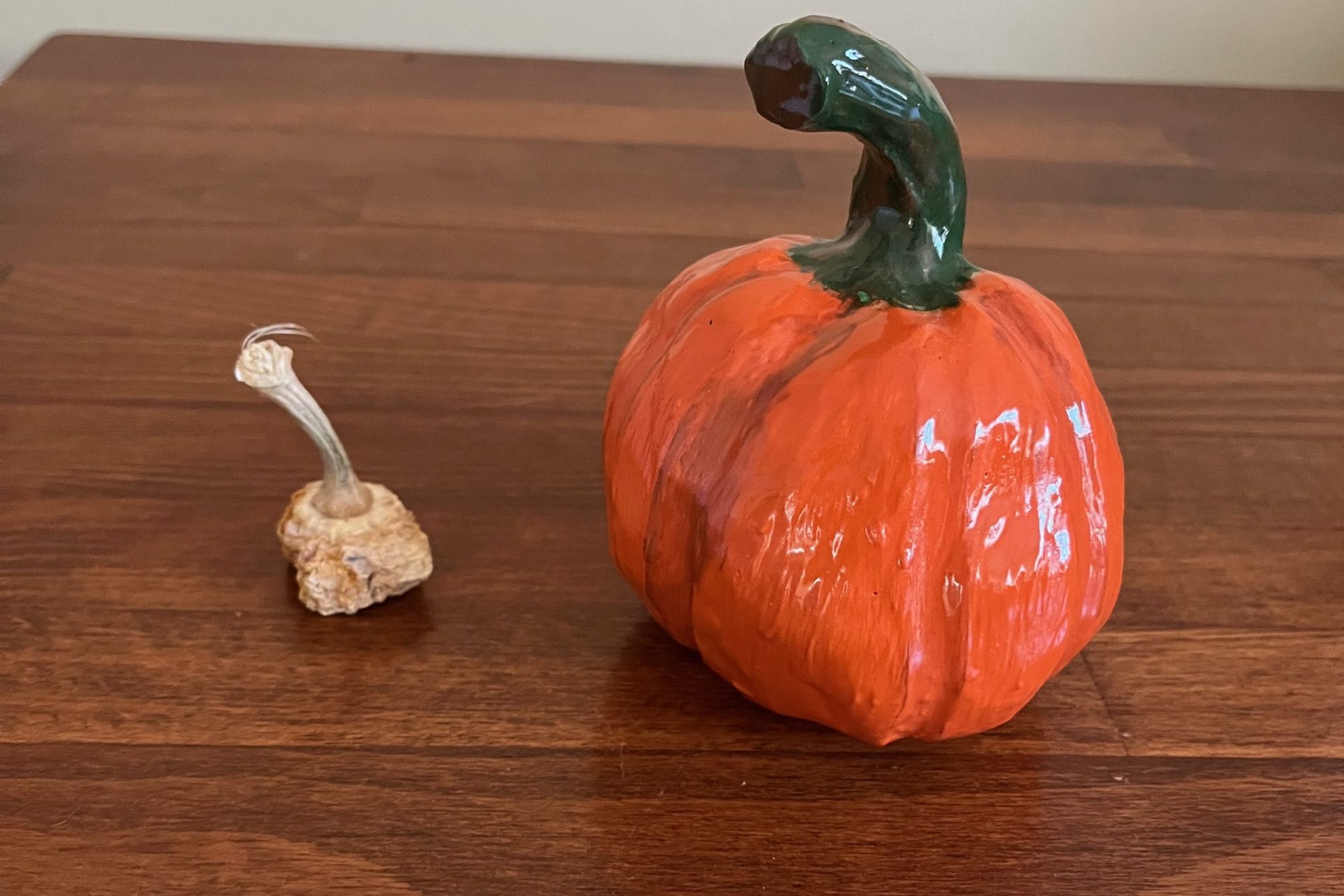 two pumpkins - one shriveled and one handmade in clay
